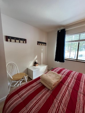A bedroom with a bed, a chair, a small table, and a window with curtains. - Meadow Drive Home In Beautiful Lake Tahoe Nevada (Stateline)