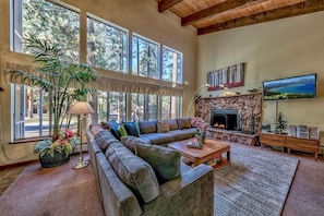 A spacious living room with a large sectional sofa, a fireplace, and a television mounted on the wall. - Meadow Drive Home In Beautiful Lake Tahoe Nevada (Stateline)