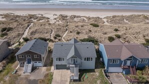 A coastal residential area with houses near the beach, featuring a sandy landscape and a view of the ocean.