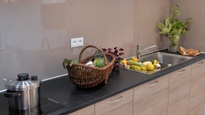 A kitchen with a black countertop, a stainless steel coffee maker, a wicker basket with vegetables, a vase with a plant, and a sink. - Upscale apartment in the heart of the historic center of Colmar (Colmar)