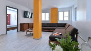 A modern living room with a sectional sofa, a coffee table, and a TV mounted on the wall. - Upscale apartment in the heart of the historic center of Colmar (Colmar)