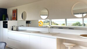 Une cuisine moderne avec des armoires blanches, un four encastré, une grande fenêtre offrant une belle vue et trois miroirs ronds accrochés au mur.