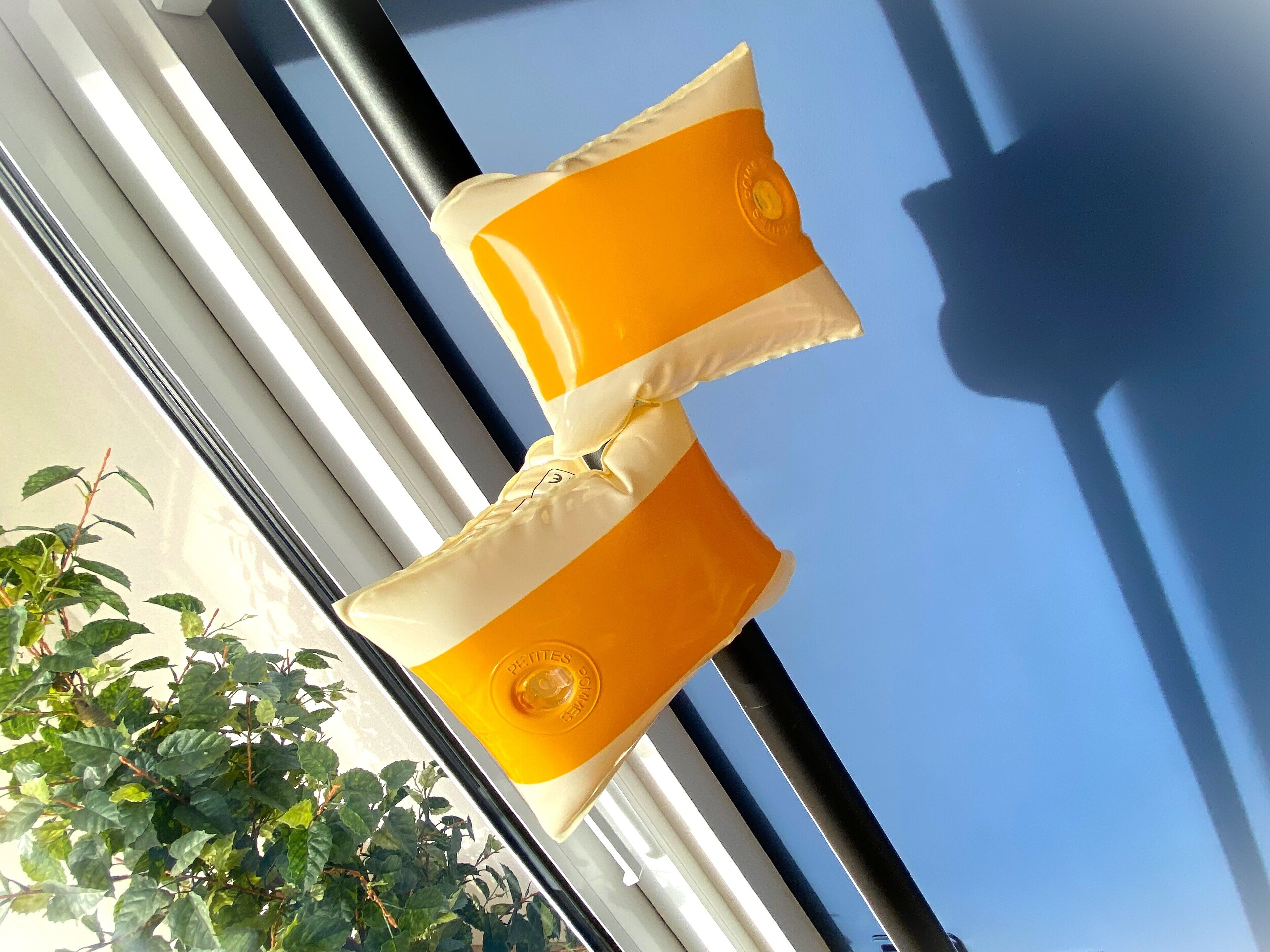 Two yellow chairs with white cushions hanging on a balcony railing.