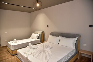 A hotel room with two beds, a wooden floor, and a modern chandelier.