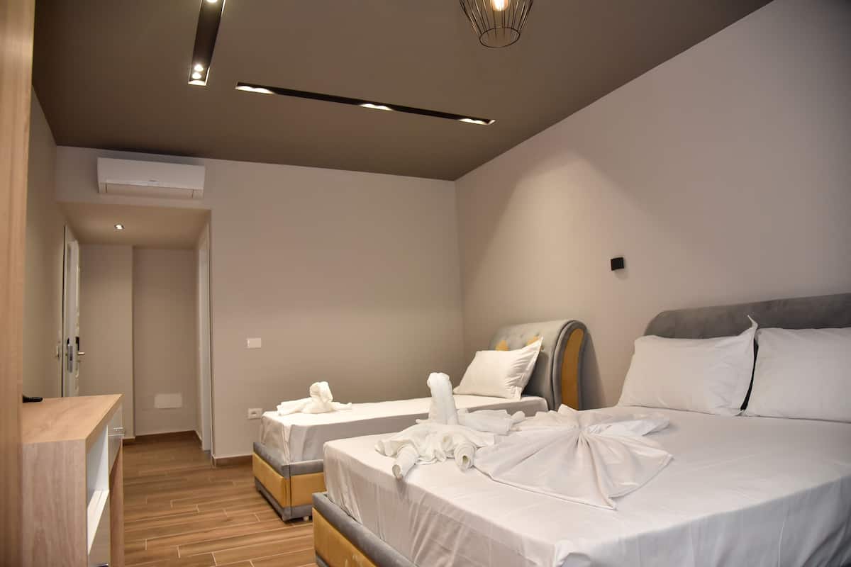 A modern hotel room with two beds, a wooden floor, and a built-in wardrobe.