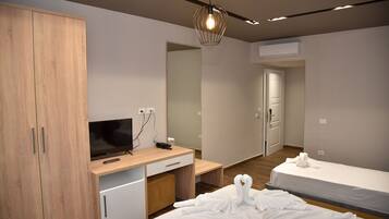 Une chambre d’hôtel moderne avec une armoire en bois, un bureau doté d’un téléviseur à écran plat, un miroir et deux lits.