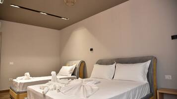 A hotel room with two beds, each with neatly folded towels, a bedside table, and a modern light fixture.