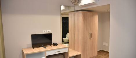 A modern bedroom with a wooden desk, a television, and a wardrobe.