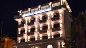 A multi-story hotel with illuminated balconies and a prominent entrance with arches. - Dolanit Hotels Lubjana (Durrës)