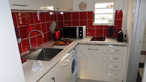 A compact kitchen with a washing machine, a microwave, and a sink. - Beautiful T2 apartment Clear view between sea and mountain near the lagoon (La Saline-Les-Bains)