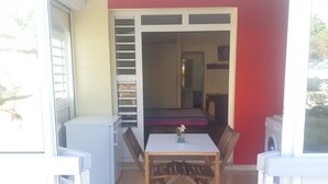 A compact room with a small table and chairs, a white cabinet, and a red wall. - Charming BOUNTY studio, swimming pool and beaches 2 minutes walk (Sainte-Luce)
