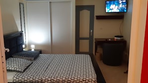 A bedroom with a bed, a TV, a desk, and a wardrobe. - Charming BOUNTY studio, swimming pool and beaches 2 minutes walk (Sainte-Luce)