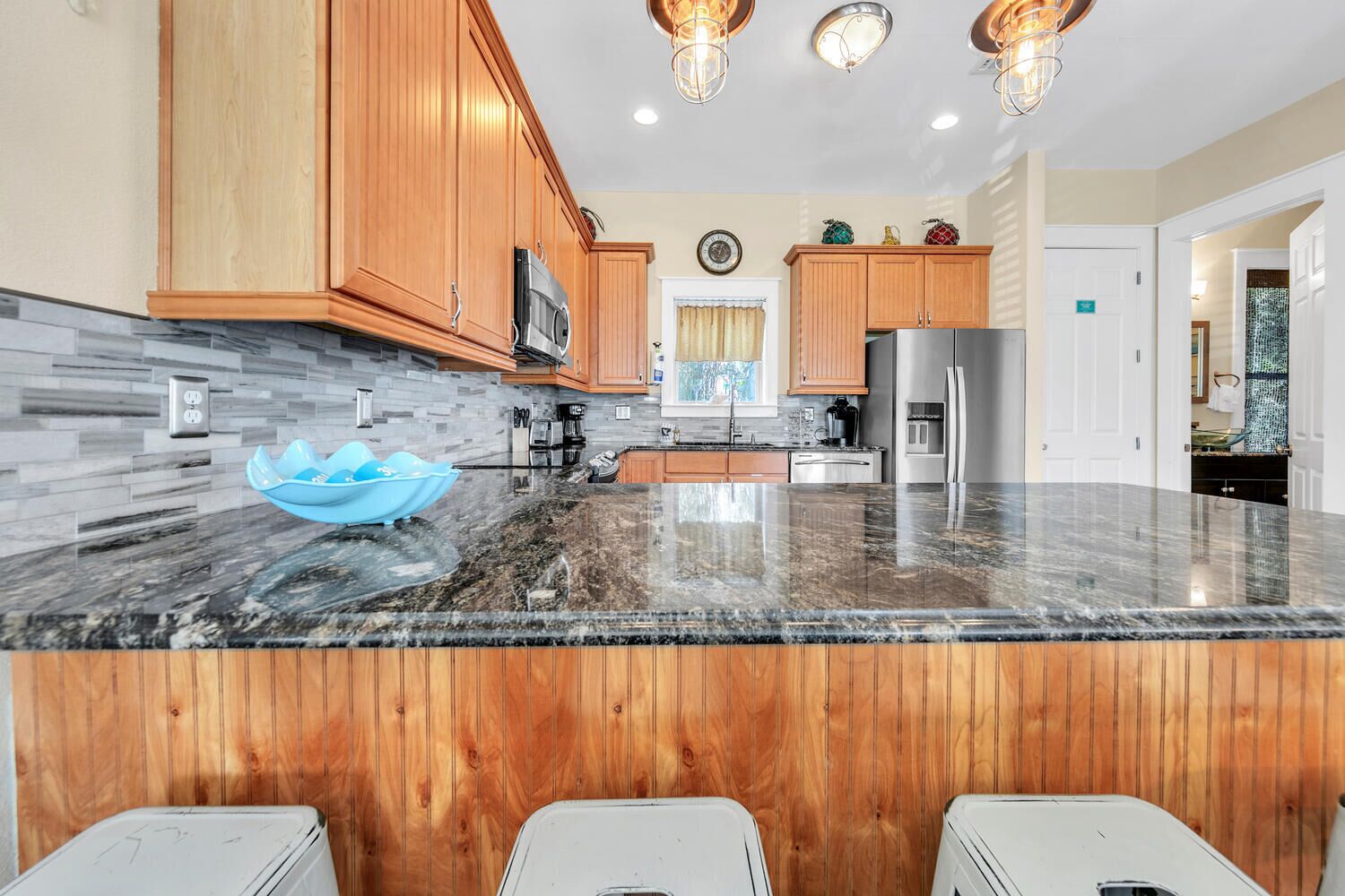 A modern kitchen with wooden cabinets, a granite countertop, and stainless steel appliances.
