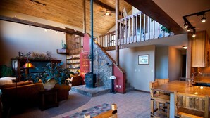 Un vaste espace de vie doté d’une cheminée, de meubles en bois, d’un escalier et d’un coin repas.