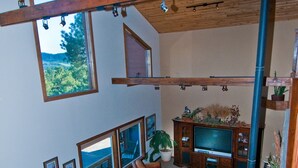 Un salon spacieux avec une grande télévision, des canapés en cuir et une cheminée en pierre.