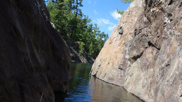 A narrow waterway flanked by rocky cliffs and dense greenery.