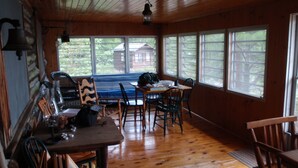 A wooden cabin interior with a dining table, chairs, and a blue couch.