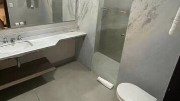 Uma casa de banho moderna com lavatório de mármore, cabine de duche em vidro e sanita.