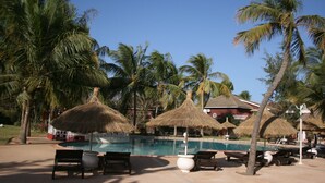 A poolside area with lounge chairs, thatched umbrellas, and palm trees. - ONE OF THE MOST ELEGANT VILLAS IN THE SMALL COAST (Saly)