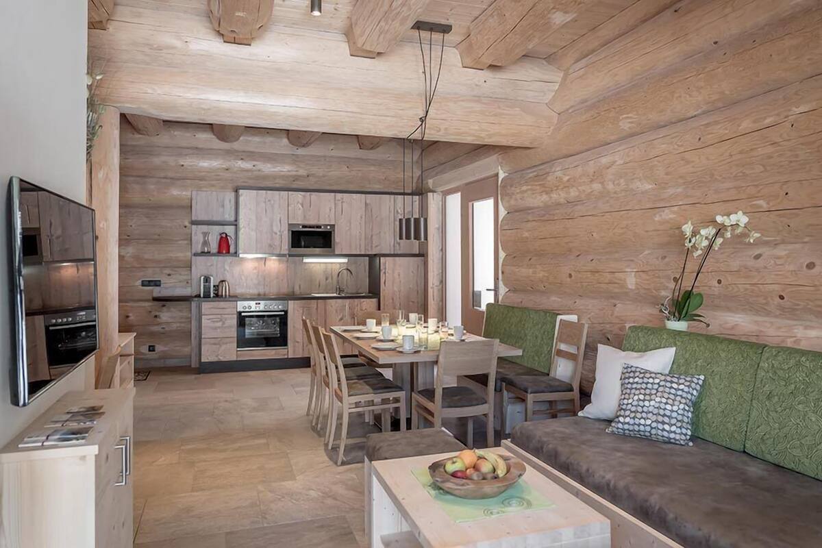 Una cocina moderna con armarios de madera y un comedor con sofá verde y frutero.
