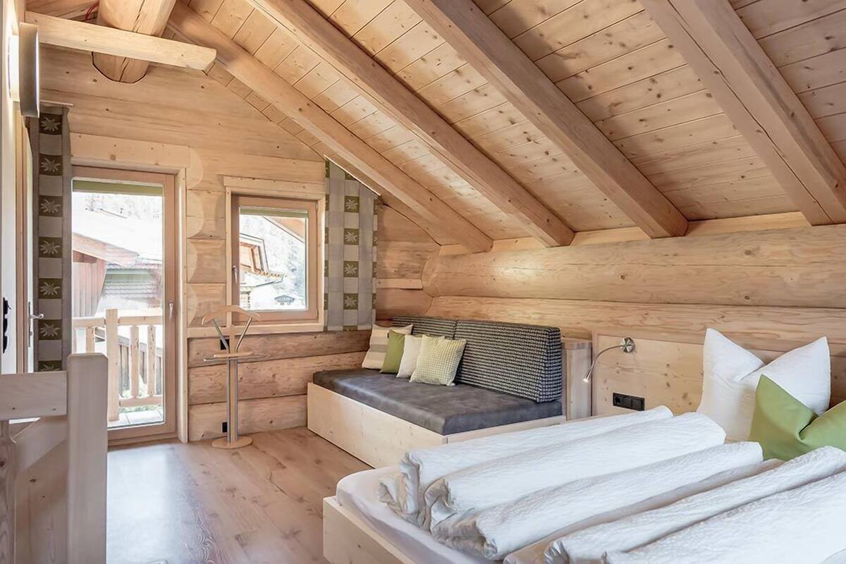 Acogedor dormitorio tipo cabaña de madera con cama, un banco y una ventana.