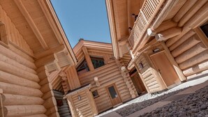 Eine Blockhütte mit steilem Satteldach, zahlreichen Fenstern und einem hölzernen Balkon.