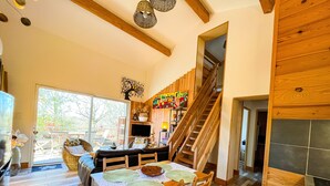 A dining area with a wooden table, chairs, and a staircase leading to a loft. - Gîte dans les bois - Nordic SPA & Nature (Montdurausse)