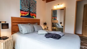 A neatly made bed with pillows, a bedside lamp, and a painting above it. - Gîte dans les bois - Nordic SPA & Nature (Montdurausse)