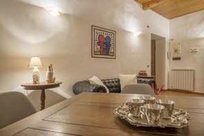 Un comedor con una mesa de madera, una lámpara y una obra de arte enmarcada en la pared.