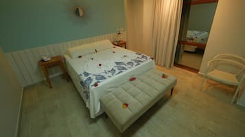 A bedroom with a bed, bedside tables, a mirror, a bench, and a chair.