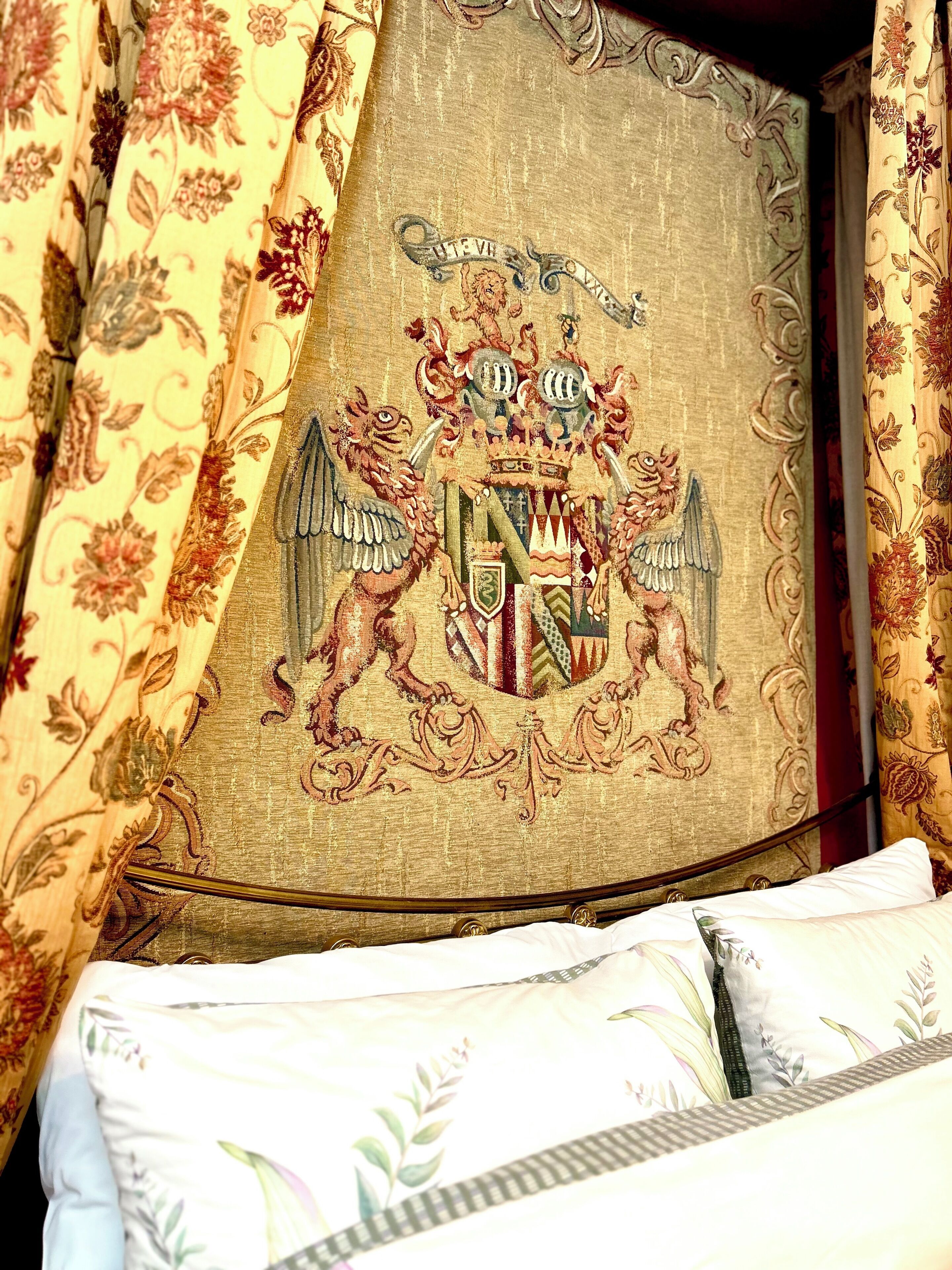 Un lit doté d’une tête de lit décorative ornée d’un blason brodé.