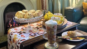 Una stanza accogliente con camino, una libreria e un tavolo apparecchiato con pasticcini e tè.