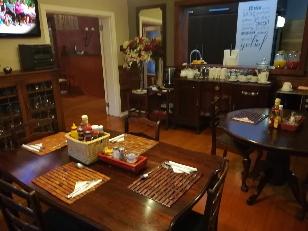 A dining area with a wooden table set for a meal, a bar area with a counter and various items, and a television mounted on the wall.