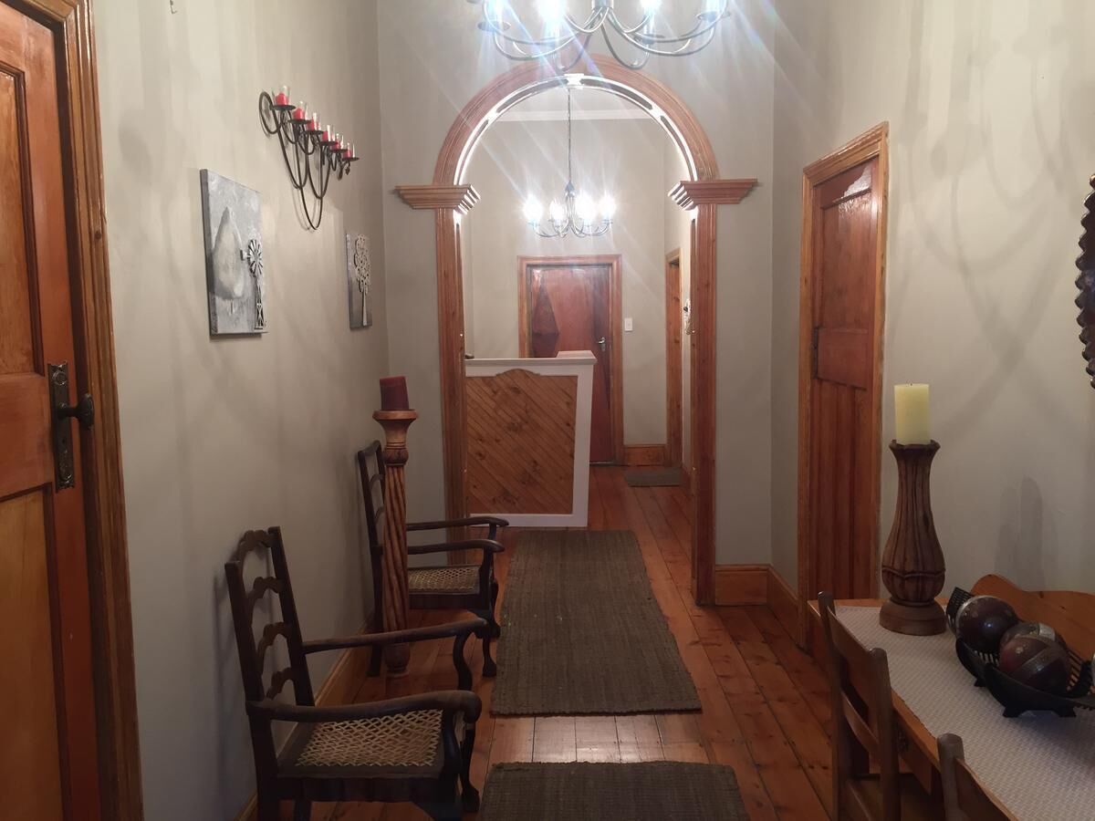Un couloir avec des portes en bois, un coin repas avec une table et des chaises, et un lustre.