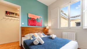 A bedroom with a wooden headboard, a bed with a blue and white striped bedspread, and a painting of red pumpkins on the wall.