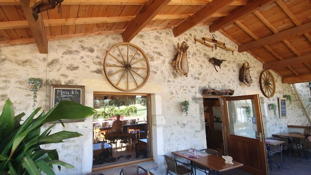 A rustic stone building with wooden beams, a large wheel, and a chalkboard menu. - Cottage 8 ps. 3 cbres. Swimming pool. Center Drôme, ideal for discovering Drome and Ardéche (Grane)