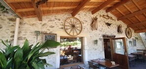 A rustic stone building with wooden beams, a large wheel, and a chalkboard menu. - Cottage 8 ps. 3 cbres. Swimming pool. Center Drôme, ideal for discovering Drome and Ardéche (Grane)