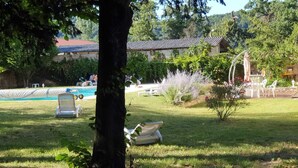 A pool area with lounge chairs, a small garden with a tree, and a building with a tiled roof. - Cottage 8 ps. 3 cbres. Swimming pool. Center Drôme, ideal for discovering Drome and Ardéche (Grane)