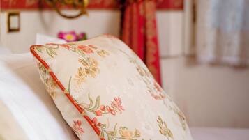Una cama con almohadas de estampado floral y una mesita de noche con lámpara.