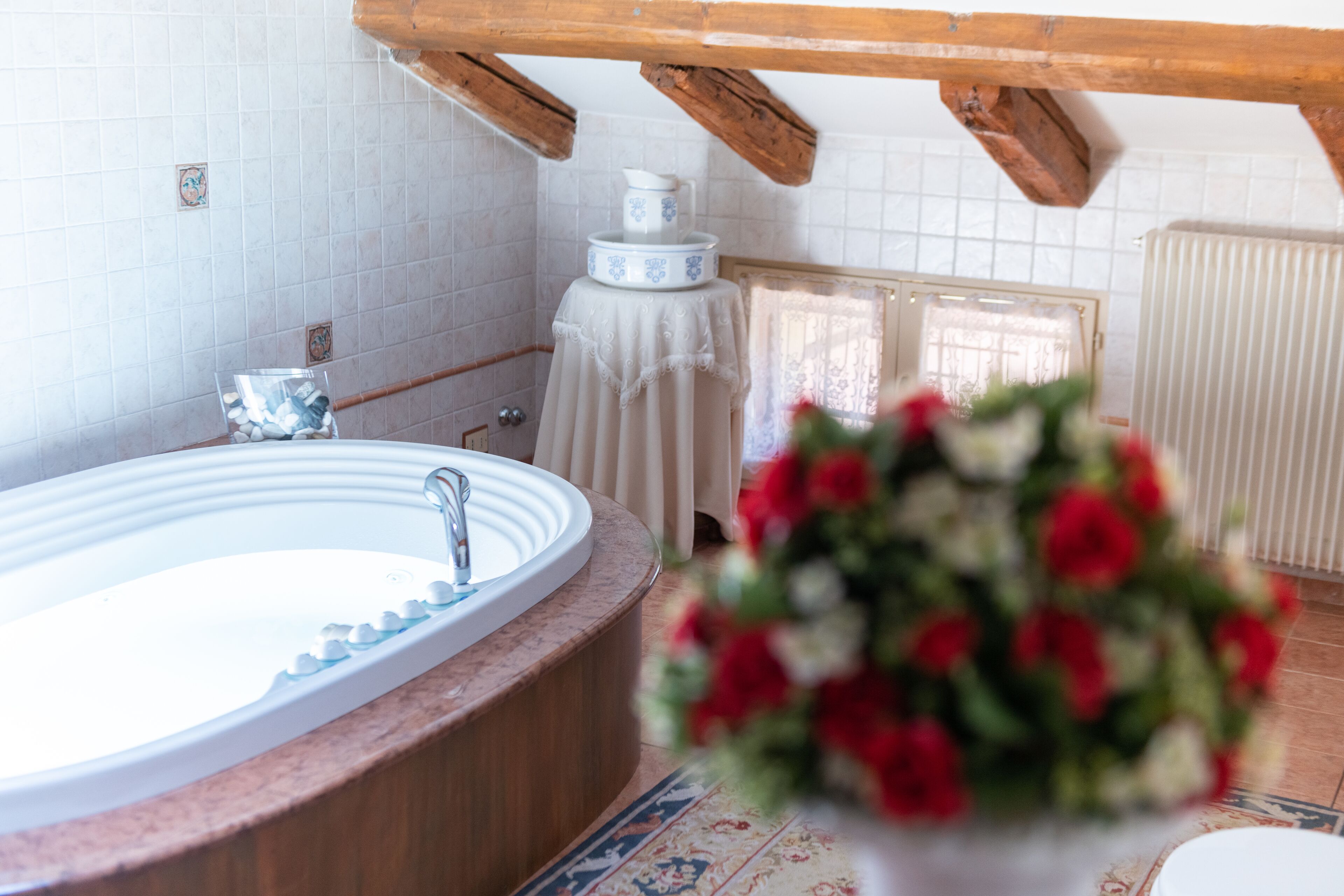 A bathroom with a bathtub, a sink, and a toilet. There is a wooden ceiling and a tiled wall.