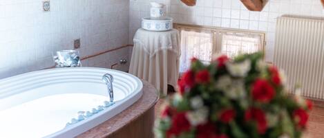 Un baño con bañera, lavamanos e inodoro. Tiene techo de madera y pared de azulejos.