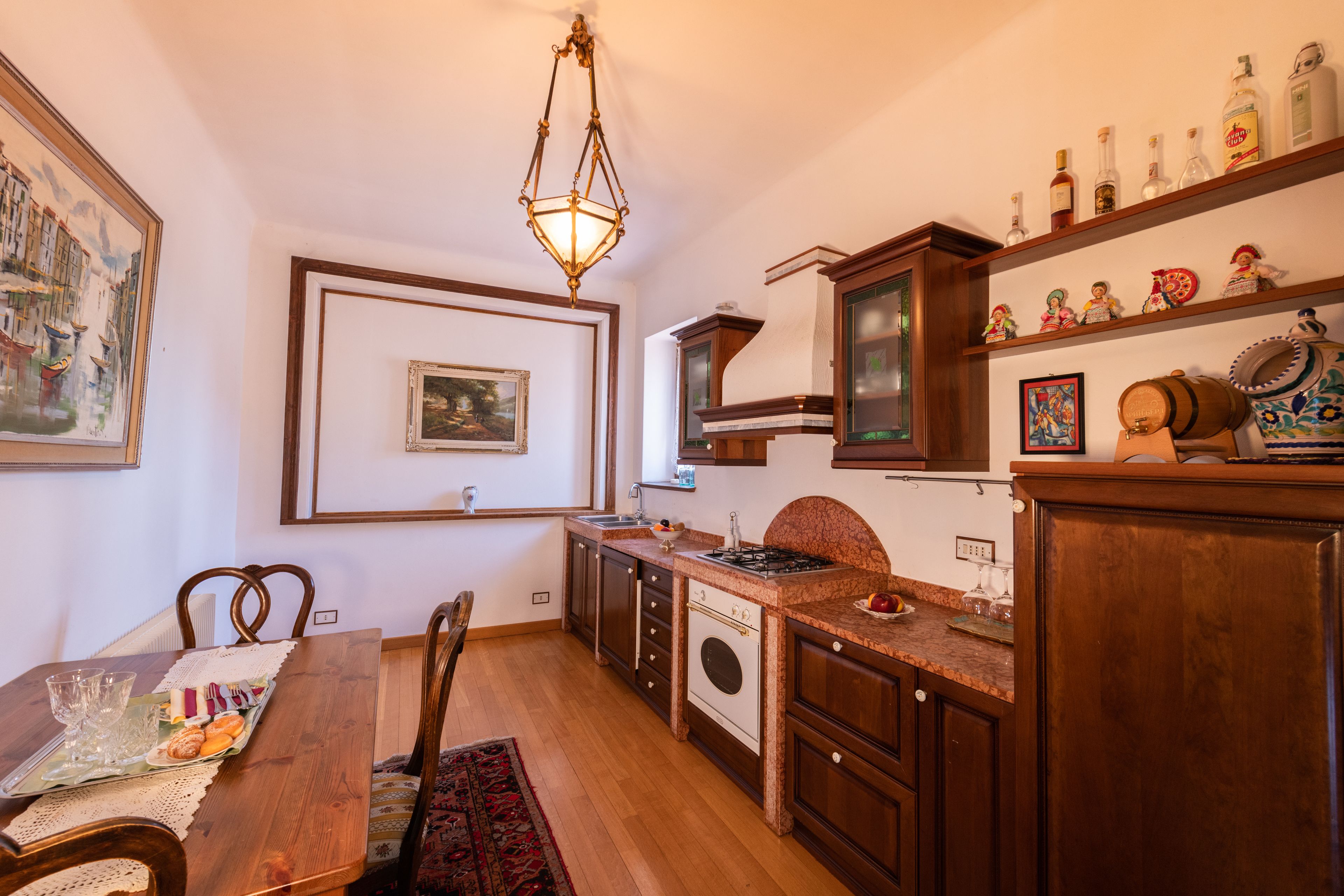 A kitchen with wooden cabinets, a stove, and a hanging light fixture.