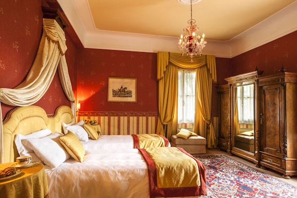 A room with a large bed, a wooden wardrobe, and a chandelier. - Castello di Spessa Golf & Wine Resort (Capriva del Friuli)