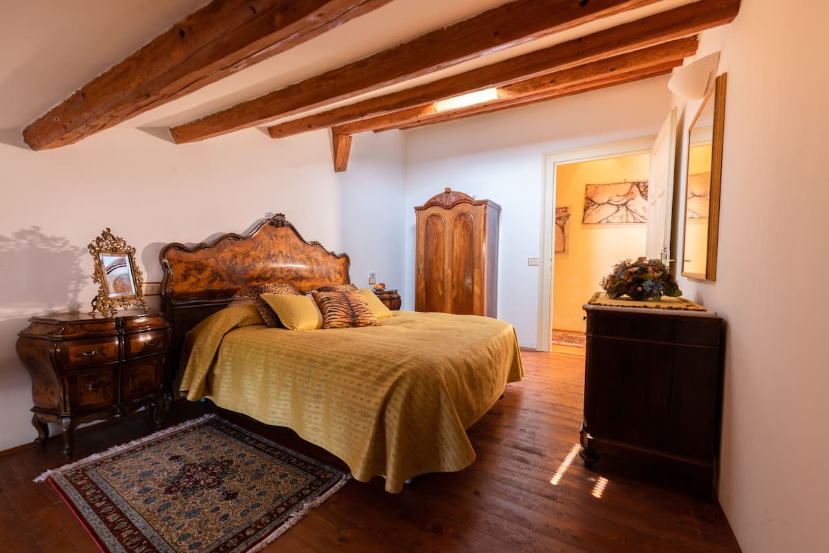 Un dormitorio con cama de madera, mesita de noche, cómoda y alfombra grande.