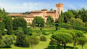 A large, historic building with multiple towers and a well-maintained garden.