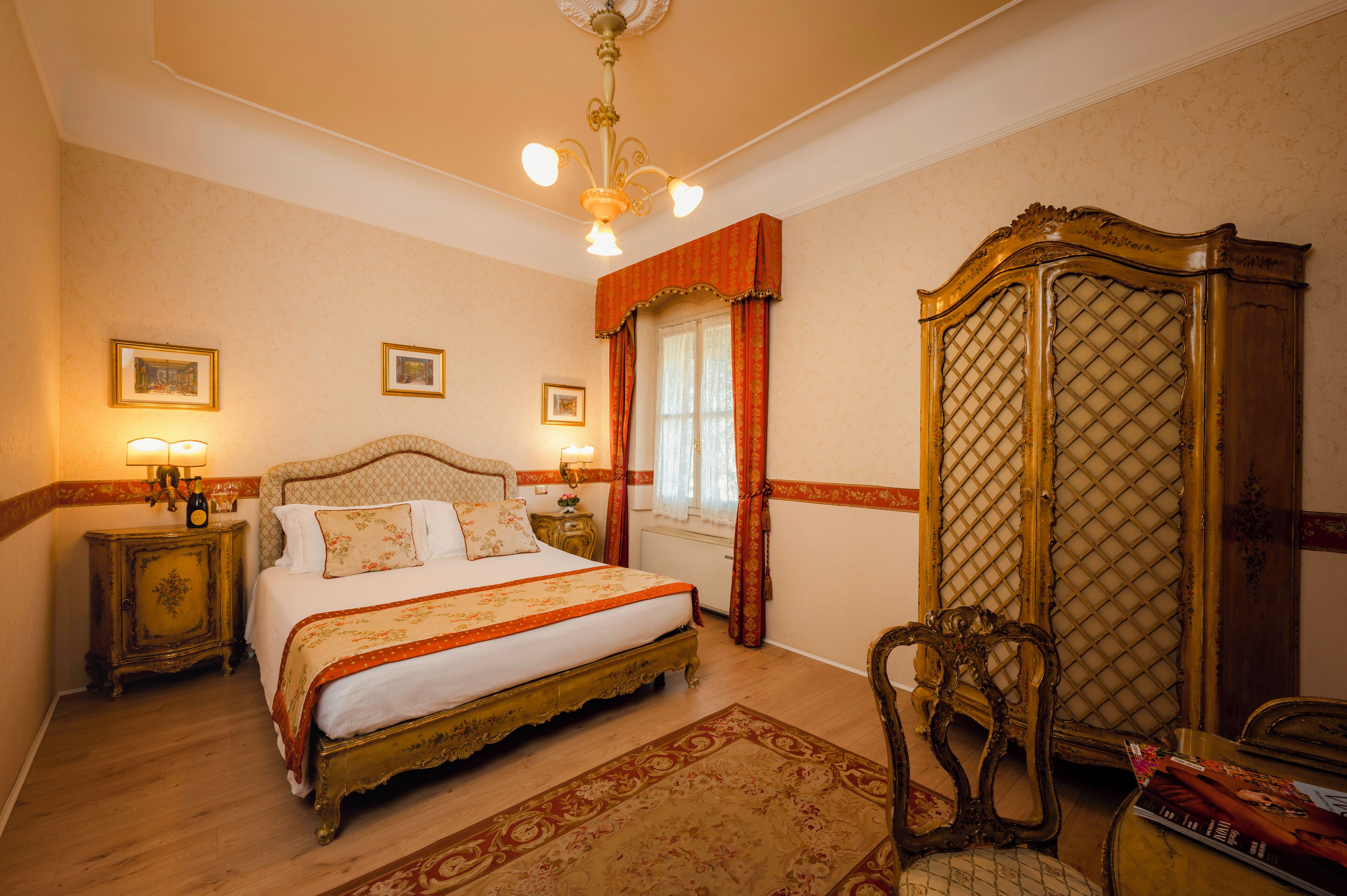 A classic bedroom with a four-poster bed, a wooden wardrobe, and a chandelier.