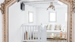 A white room with a white crib, a white sofa, and a round coffee table with decorative items.