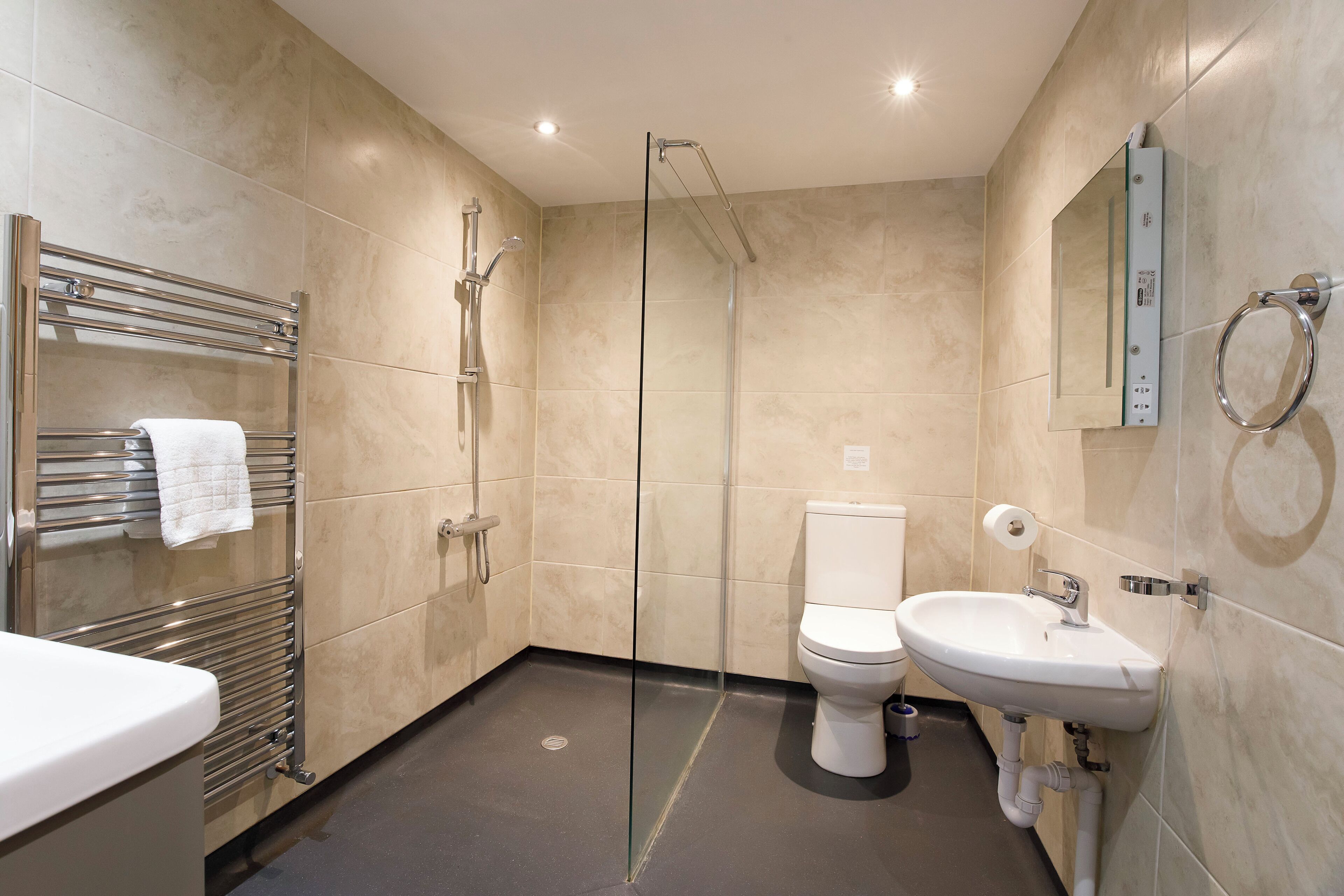 A modern bathroom with a glass-enclosed shower, a white sink, and a toilet.