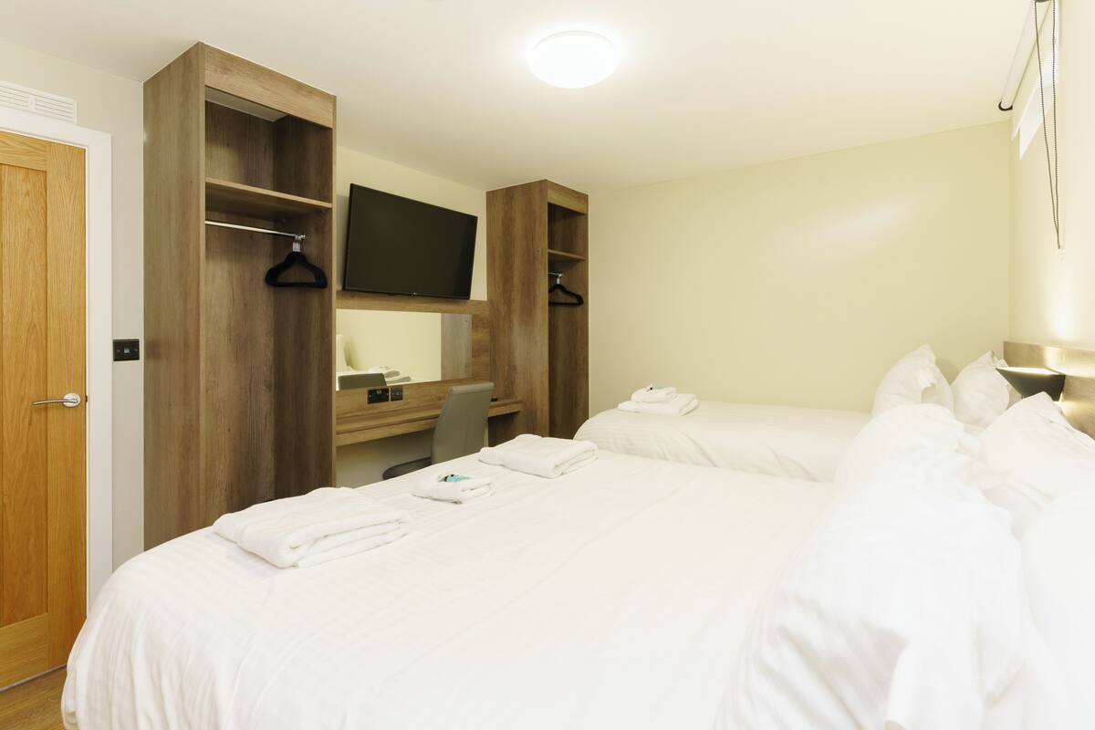 Habitación de hotel con una cama grande, un armario de madera, un televisor de pantalla plana y un escritorio con una silla.
