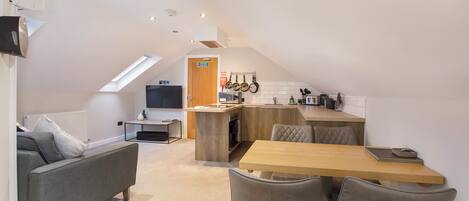 A modern loft apartment with a dining area, kitchenette, and a cozy seating area.